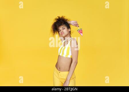 Cool african gen z teen fille tenir des bonbons isolés sur fond jaune d'été. Banque D'Images
