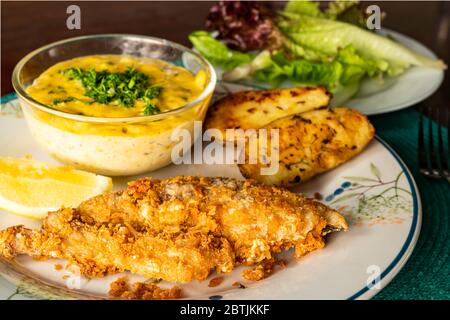 Poisson frit avec légumes et morceau de citron sur plaque de céramique. Banque D'Images