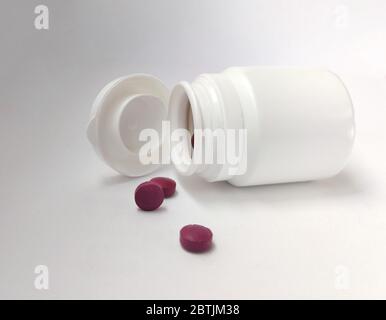 Petite bouteille en plastique blanc avec des pilules violettes. Modèle de maquette. Jar isolé sur fond blanc. Banque D'Images