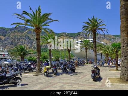 Kotor, Monténégro. Parking moto, bateau de croisière dans le port et touristes sur la place près de la porte de mer de la vieille ville de Kotor Banque D'Images