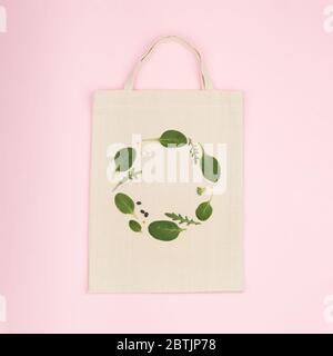 Sac écologique en toile avec composition verte créative en feuilles d'épinards verts, rucola et haricots. Vue de la pose à plat sur fond rose Banque D'Images