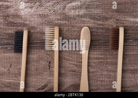 Haut au-dessus de la tête plat plat plat plat plat plat plan gros plan macro photo de quatre brosses à dents de noir blanc beige et brun de couleurs isolées sur le bois rustique backgrou Banque D'Images