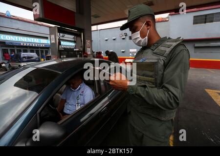 Caracas, Venezuela. 26 mai 2020. Un soldat de la Garde nationale bolivarienne effectue des contrôles dans une station-service au milieu de la pénurie continue de carburant. Les voitures peuvent remplir jusqu'à 30 litres de carburant. Le Venezuela possède d'énormes réserves de pétrole, mais en raison d'un manque de capacité de raffinage, il a beaucoup trop peu d'essence. Selon les informations iraniennes, le premier de plusieurs pétroliers iraniens avec de l'essence pour le Venezuela devrait avoir atteint le pays sud-américain d'ici la fin mai 2020. Crédit : Pedro Rances Mattey/dpa/Alay Live News Banque D'Images