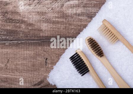 Vue du dessus de la tête photo de trois brosses à dents en bambou sur une serviette sur fond de bois Banque D'Images