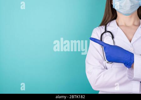 Photo courte de femme professionnelle médecin qualifié montrant avec le doigt un espace vide portant une blouse de laboratoire uniforme blanche isolée sur le sarcelle Banque D'Images