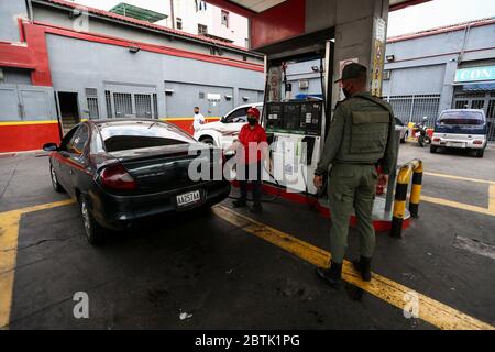 Caracas, Venezuela. 26 mai 2020. Un soldat de la Garde nationale bolivarienne vérifie les documents auprès d'une conductrice avec un garde-bouche qui fait la queue devant une station-service pendant la pénurie de carburant. Le Venezuela possède d'énormes réserves de pétrole, mais en raison d'un manque de capacité de raffinage, il a beaucoup trop peu d'essence. Selon les informations iraniennes, le premier de plusieurs pétroliers iraniens avec de l'essence pour le Venezuela a atteint le pays sud-américain. Les voitures sont actuellement autorisées à remplir jusqu'à 30 litres de carburant. Crédit : Pedro Rances Mattey/dpa/Alay Live News Banque D'Images