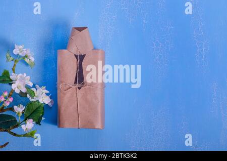 Concept de fête des pères. Bonne journée des pères. Boîte cadeau sous forme de chemise sur fond bleu avec fleurs et espace pour copier. Carte de vœux Banque D'Images