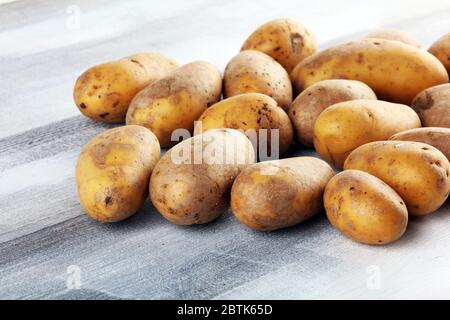 Pile de pommes de terre couchée sur des planches de bois. Pommes de terre fraîches sur fond rustique Banque D'Images