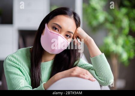 Photo de joli mais triste virus corona malade patient homey asiatique femme assis canapé tête maigre à la main moody manquant promenades dehors besoin de garder Banque D'Images