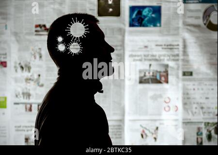 Silhouette d'un homme avec une molécule de coronavirus dans sa tête sur le fond des articles de journaux, comme symbole de la propagande pandémique. Banque D'Images