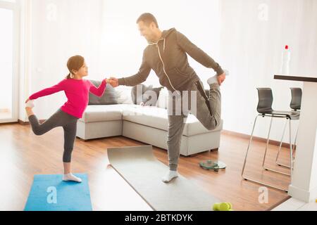 père et fille sont formation à la maison. Entraînement dans l'appartement. Sports à la maison. Ils font des exercices avec le yoga ou le Pilates Banque D'Images