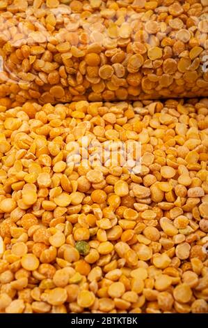 Pois jaunes dans un sac en plastique et céréales en vrac sur fond de toile de fond à texture rugueuse. Céréales traditionnelles pour faire des soupes et du porridg Banque D'Images