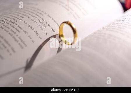 Un anneau de mariage sur la bible avec l'ombre de la forme de coeur sur la page Banque D'Images