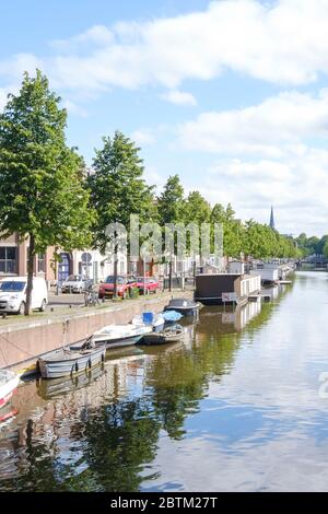 La Haye, pays-Bas - Mai 15 2020 : Canal avec réflexion de bateaux et d'arbres, rue remplie de voitures et de maisons à la Haye, pays-Bas. Banque D'Images