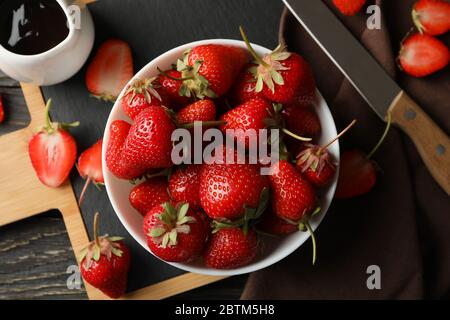 Composition avec bol de fraise savoureuse sur table en bois. Baies d'été Banque D'Images