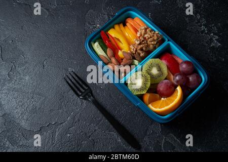 Vue de dessus de la boîte à déjeuner complète avec ses fuits, légumes et noix. Concept de collations santé. Banque D'Images