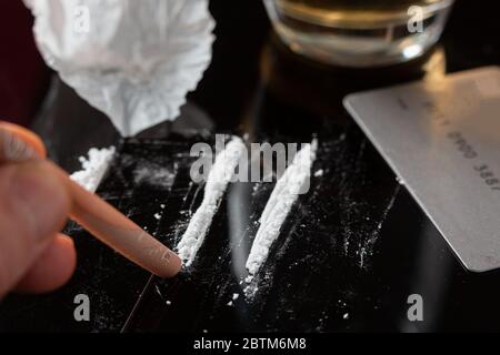 Lignes de cocaïne préparées sur une table et billets roulés prêts à être reniflés Banque D'Images
