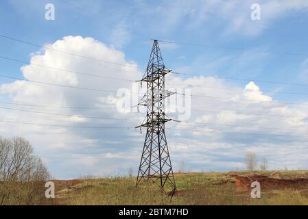 Pylône en fer d'une ligne haute tension se tient dans un champ contre un ciel bleu. Banque D'Images