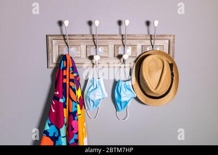 Porter une serviette de plage, un chapeau et un masque de sécurité sur le porte-vêtements Banque D'Images