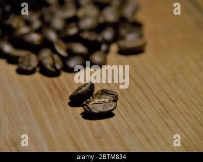 Les grains de café crus sont rapprochés sur une planche à découper en bois. Banque D'Images