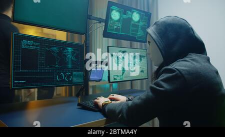 Vue latérale d'un pirate masqué qui écrit un malware dangereux. Cyber-criminel. Banque D'Images