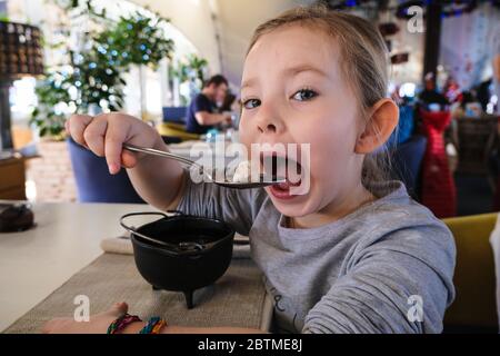 petite fille mangeant des boulettes dans le café Banque D'Images