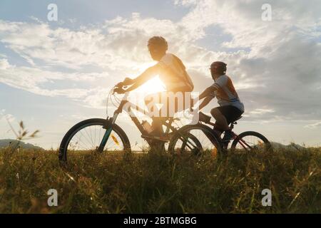 Jeune couple amoureux, amusant et heureux de faire du vélo de montagne après l'épidémie de coronavirus Covid-19. Fin de l'épidémie de coronavirus. Silhouette vélo homme A. Banque D'Images