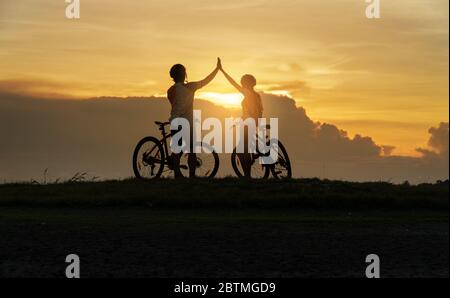 Jeune couple amoureux, amusant et heureux de faire du vélo de montagne après l'épidémie de coronavirus Covid-19. Fin de l'épidémie de coronavirus. Silhouette vélo homme A. Banque D'Images