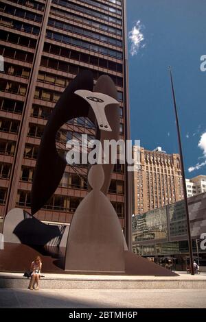 Vue verticale d'une femme assise devant la sculpture Picasso sans titre à Daley Plaza à Chicago Loop, Illinoi, USA Banque D'Images