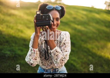 Belle fille africaine heureux de prendre des photos sur polarid appareil photo passer du temps dans le parc Banque D'Images