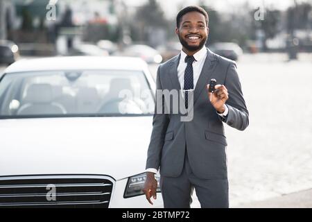 Un homme d'affaires africain heureux montrant la nouvelle clé automatique debout à l'extérieur Banque D'Images