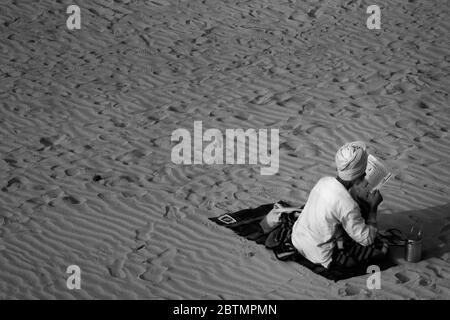 Un vieil homme avec un visage caché lisant des journaux sur la plage Banque D'Images