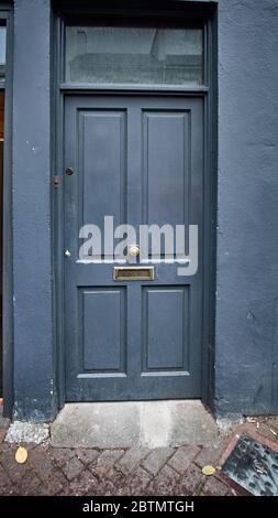 Porte peinte en quatre panneaux bleus avec tableau arrière, fente pour courrier et poignée de porte centrale en Irlande. Format vertical. moody, mystère, ouvert, fermé, passage, entrée. Banque D'Images