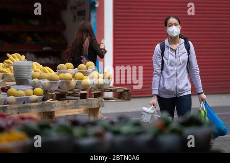 Une femme portant un masque facial regarde un marché de fruits et légumes en plein air à Walthamstow, dans l'est de Londres, après l'introduction de mesures pour mettre le pays hors de son confinement. Banque D'Images