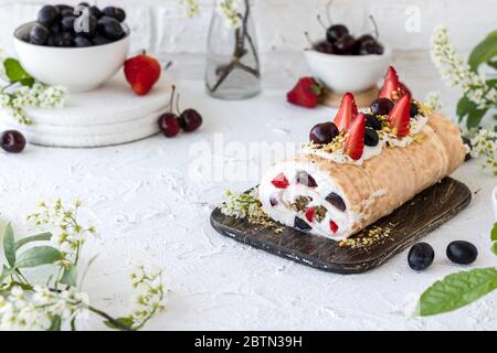 Rouleau de meringue avec baies de pralines à la pistache fraîches et crème fouettée et crème au fromage caillé. Dessert d'été Banque D'Images