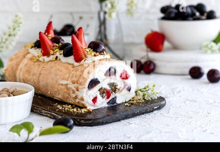 Rouleau de meringue avec baies de pralines à la pistache fraîches et crème fouettée et crème au fromage caillé. Dessert d'été Banque D'Images