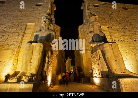 Grande statue et sculptures hiéroglypiques de Ramses II à l'entrée de l'ancien temple égyptien de Louxor illuminé la nuit Banque D'Images