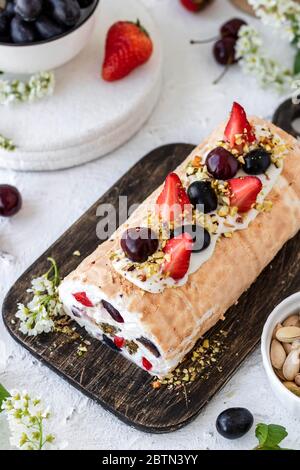 Rouleau de meringue avec baies de pralines à la pistache fraîches et crème fouettée et crème au fromage caillé. Dessert d'été Banque D'Images