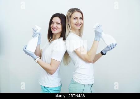 Deux femmes tiennent une bouteille vaporisée avec un antiseptique ou un détergent comme des pistolets. Concept de santé ou de nettoyage Covid-2019, sur fond blanc Banque D'Images