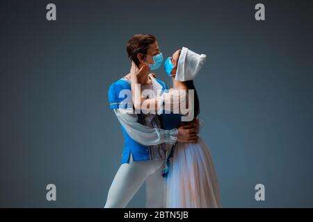 Cendrillon moderne n'essayant pas la chaussette, mais s'embrassant avec un masque facial protecteur. Jeunes danseurs de ballet gracieux pendant le spectacle en studio. Art, mouvement, flexibilité, inspiration. Banque D'Images