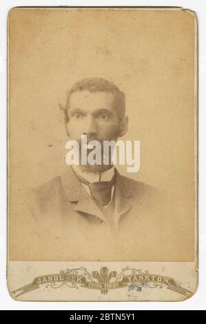 Photographie d'un homme avec une barbe. Un portrait noir et blanc de carte de cabinet d'un homme barbu. L'homme porte une veste et une cravate de couleur claire avec une chemise blanche à col haut. Banque D'Images