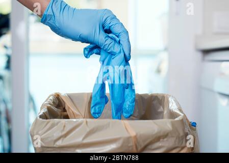 gros plan d'un homme qui jette un gant de latex usagé à la poubelle Banque D'Images