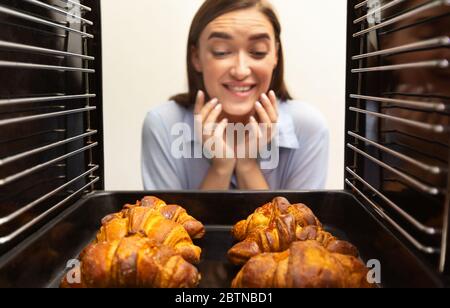 Bonne fille à la recherche de croissants frais savoureux au four Banque D'Images