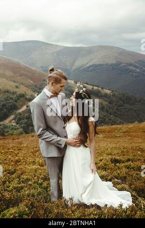 superbe mariée et marié élégant posant engagiant, couple de mariage de boho, cérémonie de luxe à la montagne avec vue incroyable Banque D'Images