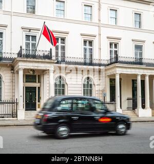 Le Haut-commissariat de Trinité-et-Tobago à Belgravia, un quartier londonien avec une forte concentration d'ambassades. Flou de mouvement sur le taxi de premier plan. Banque D'Images