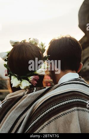 couple heureux de luxe newlyweds regardant le coucher de soleil enserrant sous un tapis rustique dans les montagnes Banque D'Images
