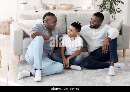 Famille masculine africaine américaine multigénérationnelle positive qui se repose chez elle ensemble Banque D'Images