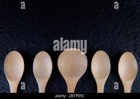 Plat Lay une cuillère en bois vide, cinq pièces placées sur un fond noir cuillère en bois vide, cinq pièces placées sur un fond noir Banque D'Images