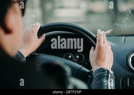 Jeune femme fume une cigarette tout en conduisant une voiture, concept de transport Banque D'Images