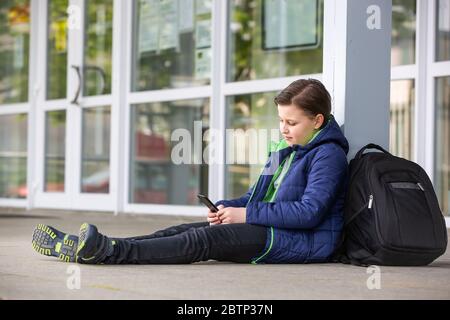 Truancy concept, jeune garçon restant loin de l'école et jouant sur le mobile, absence de l'école Banque D'Images